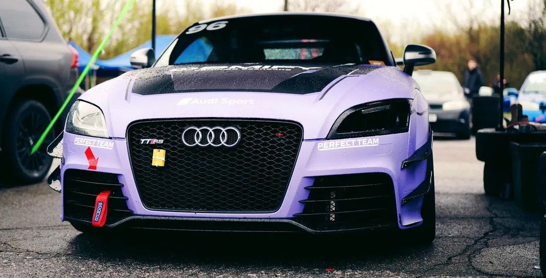 Coupé Audi TT gris posé sur une route sinueuse, mettant en valeur sa silhouette sportive et ses jantes.