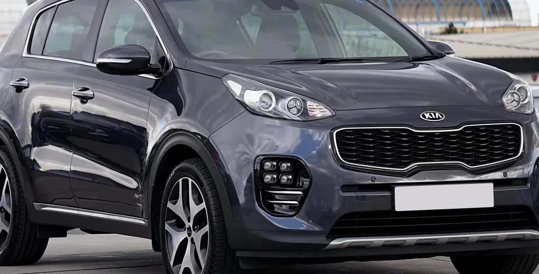 Kia Sportage hybride restylé vu de trois quarts avant sur route, carrosserie sombre et jantes alliage.